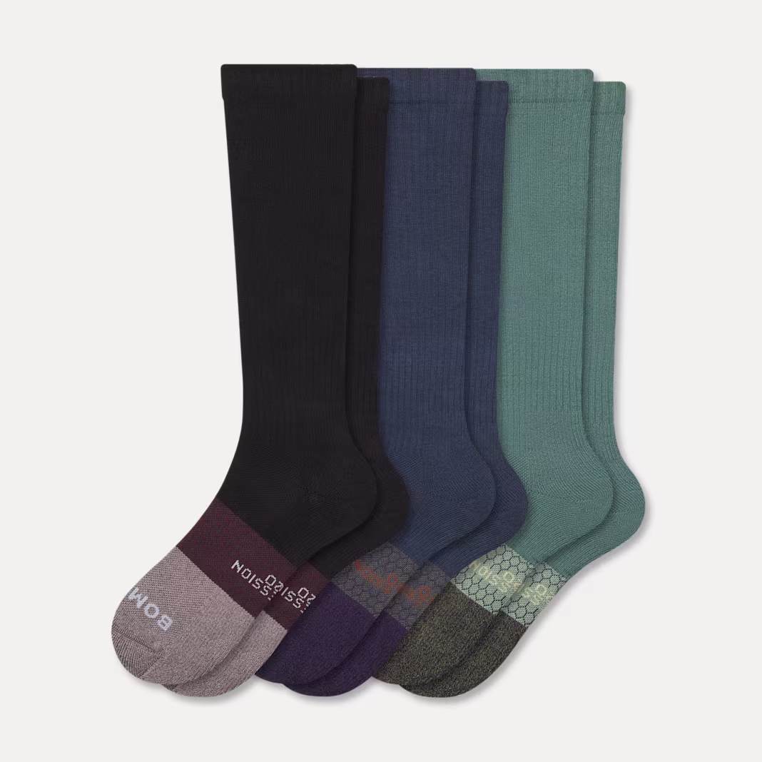Rainbow of Bombas socks fanned out on a cream backdrop