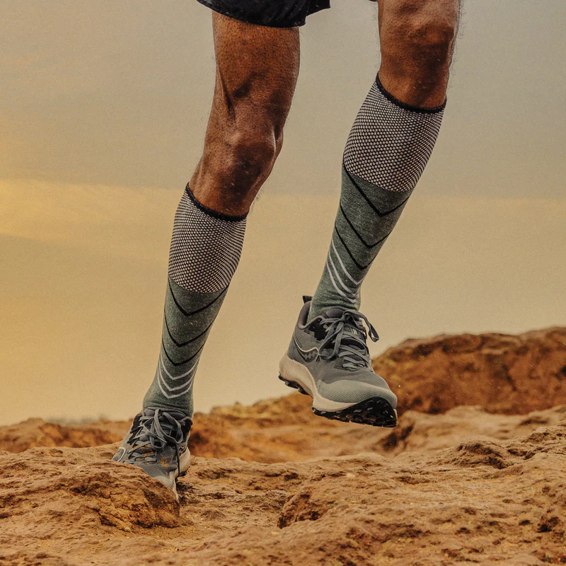 Runner wearing grey Sockwell compression socks on a rocky trail
